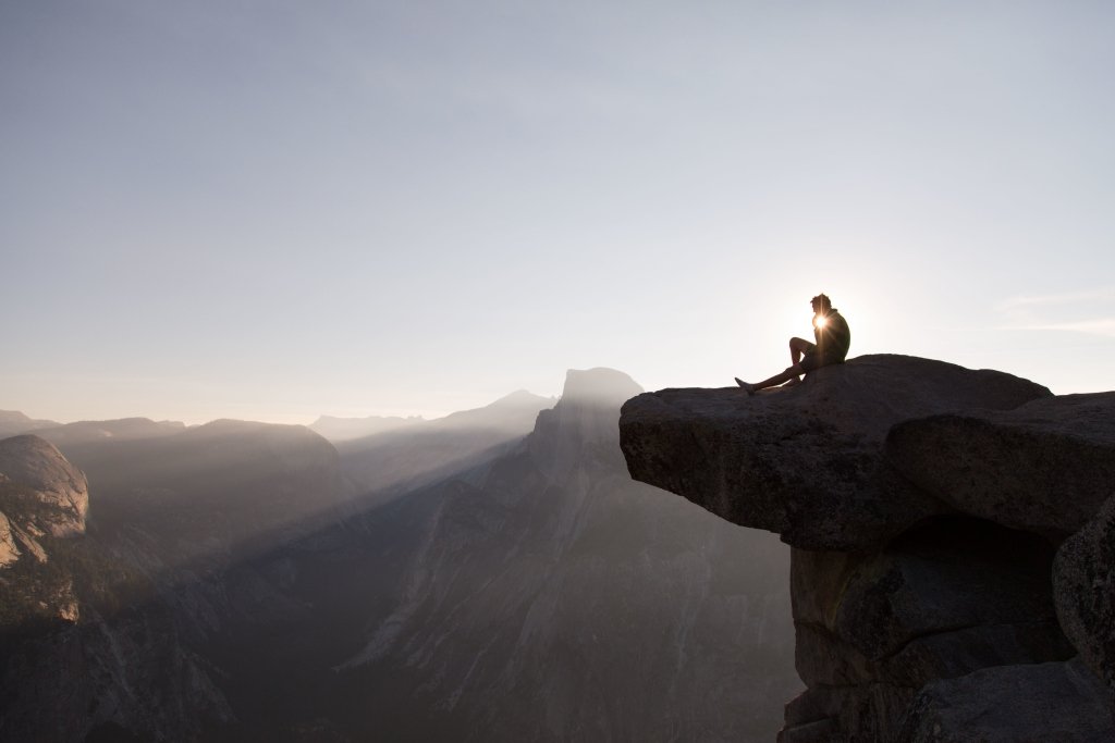 A man sitting on the top of a cliff